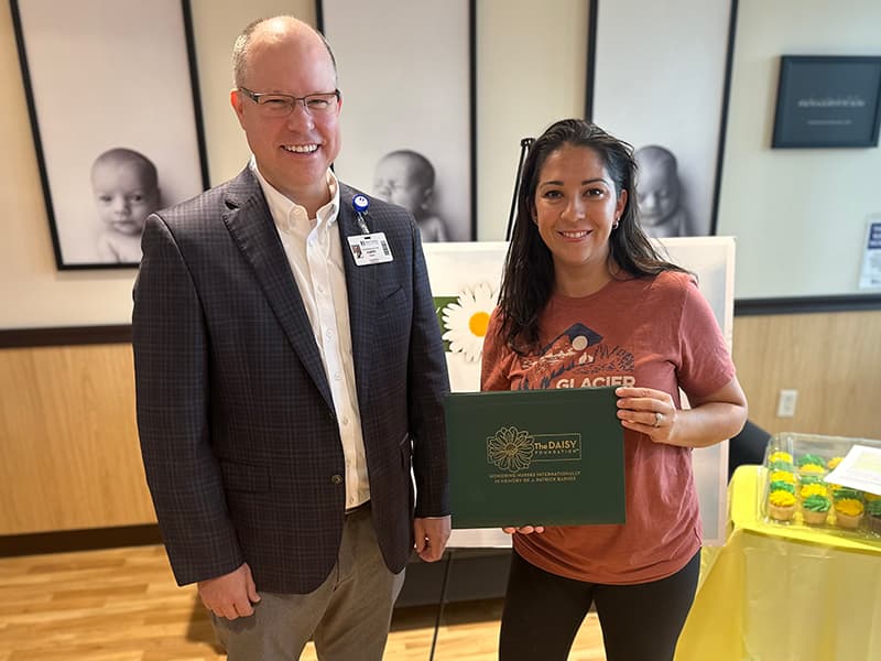 Jessica Sladek displays her DAISY Award while posing with Saint Francis President & CEO Justin Davison.